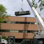 A 75-ton rooftop unit being craned to roof of an office building