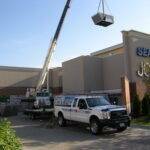 A 20-ton rooftop unit gets craned to the roof of a mall for installation by AireCom