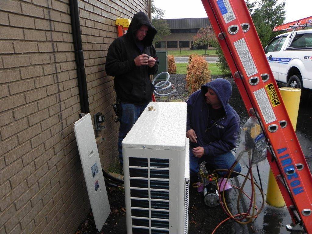 A ductless mini-split heating and cooling system being installed by AireCom technicians