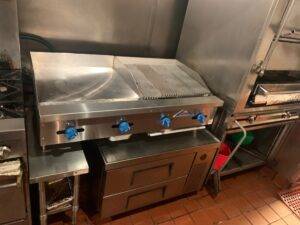 A flat top grill on top of a refrigerated base in a commercial kitchen