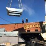 A curb adapter being crane lifted to roof in preparation for an RTU installation