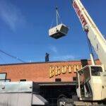 A 20-ton packaged rooftop unit being crane lifted onto a roof in downtown Columbus, Ohio