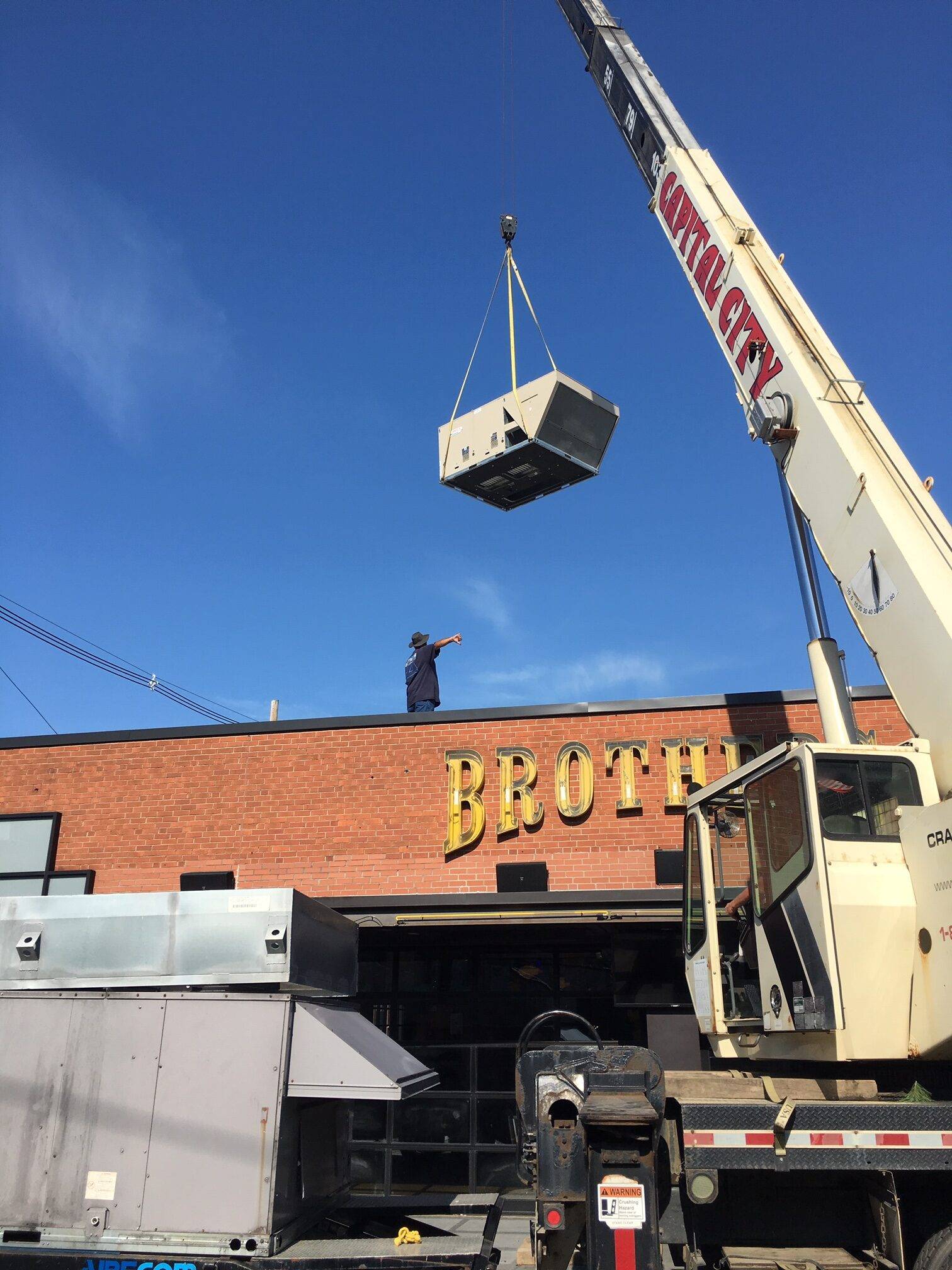 A 20-ton packaged rooftop unit being crane lifted onto a roof in downtown Columbus, Ohio