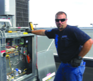 An AireCom technician preforming preventative maintenance on an HVAC unit