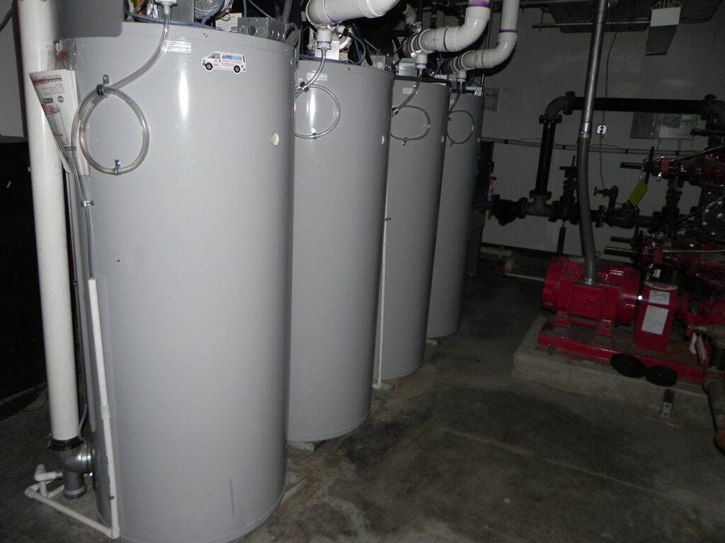 A bank of four water heaters installed in a hotel mechanical room